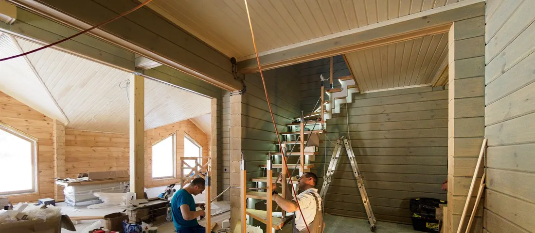 Two carpenters assembling a staircase inside a timber framed house