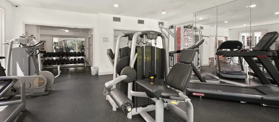 Gym with weight machines, treadmills and mirrored walls, no people