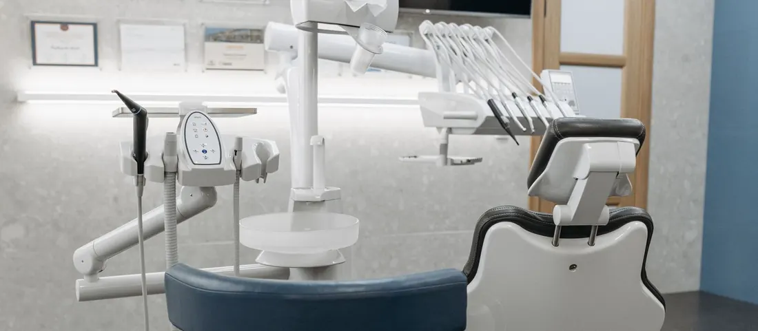 Empty dental treatment room with a patient chair, lamp and stool