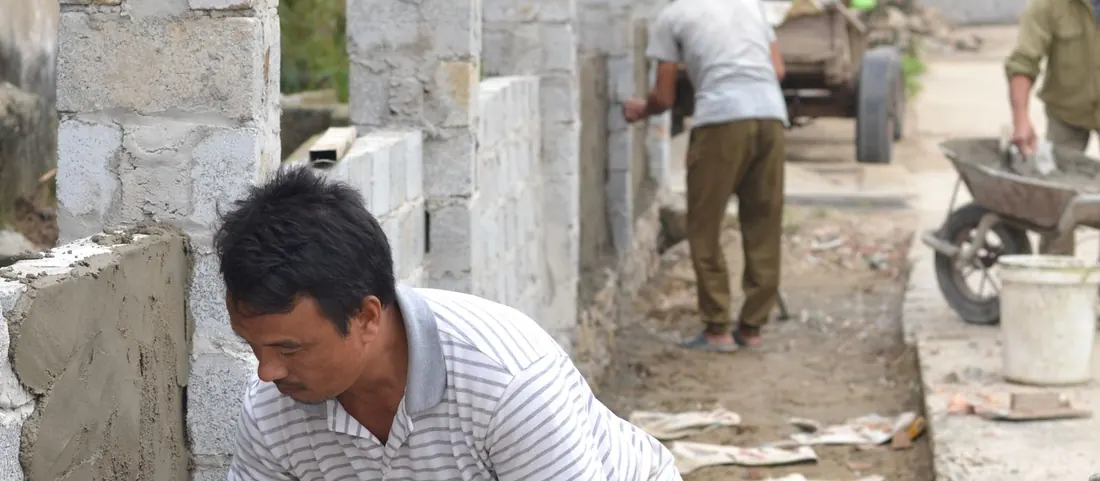 Mason spreading mortar on a concrete block wall with a trowel