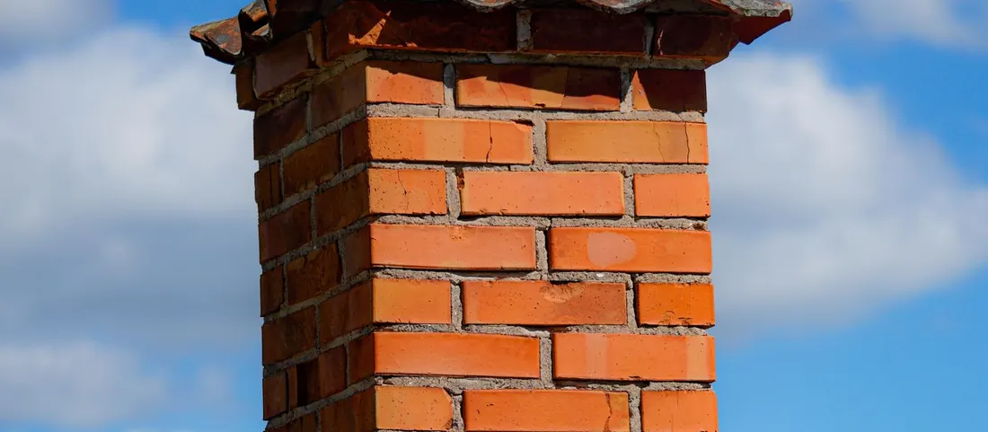Red brick chimney rising from a weathered wood shingle roof