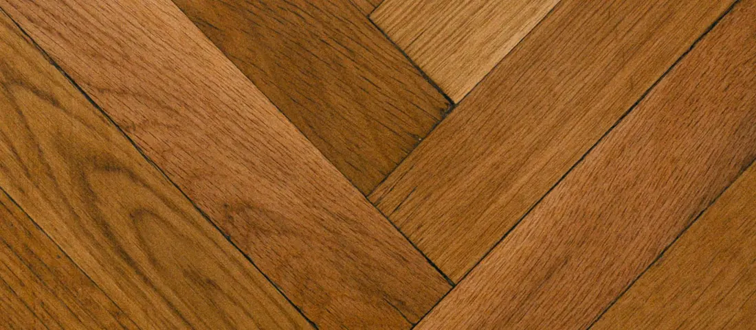 Oak strip flooring laid in a herringbone pattern with tight joints filling the frame