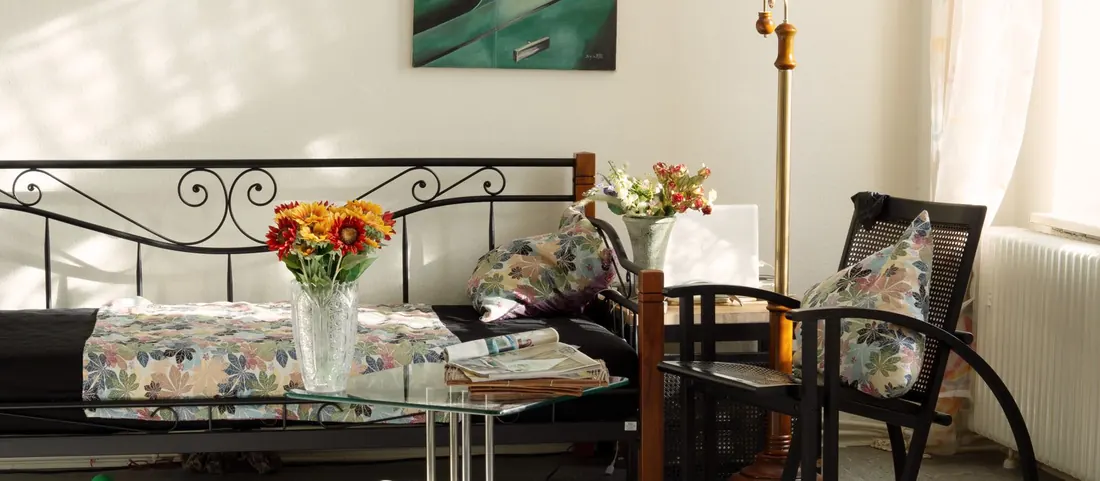 Sunlit lived in room with a daybed, cut flowers and a reading chair