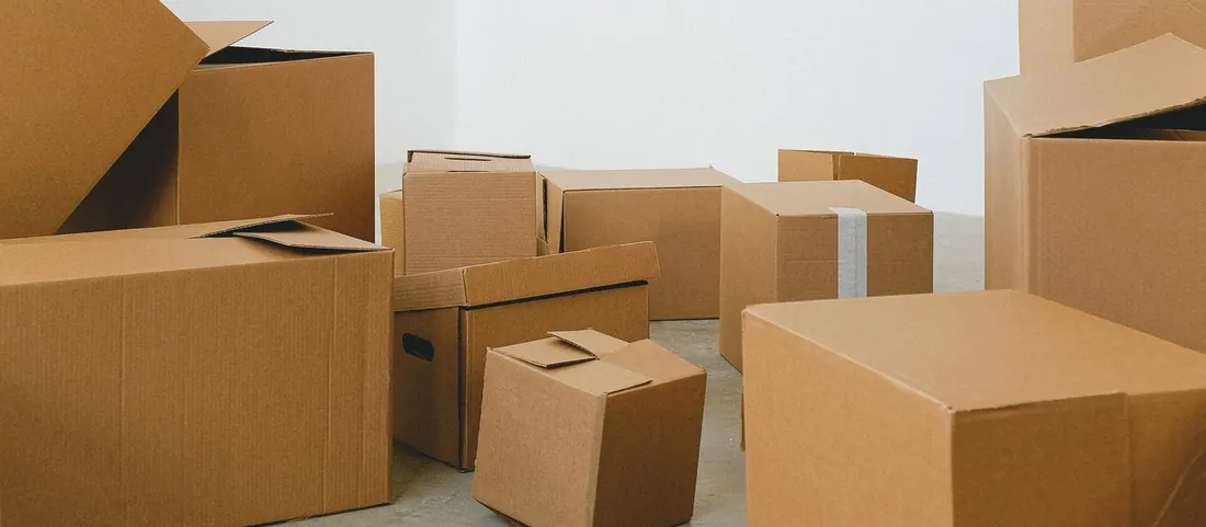 Stacks of cardboard moving boxes on the floor of an empty white room