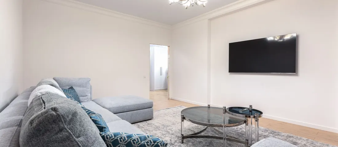 Show ready living room with a grey sectional, rug and wall mounted TV