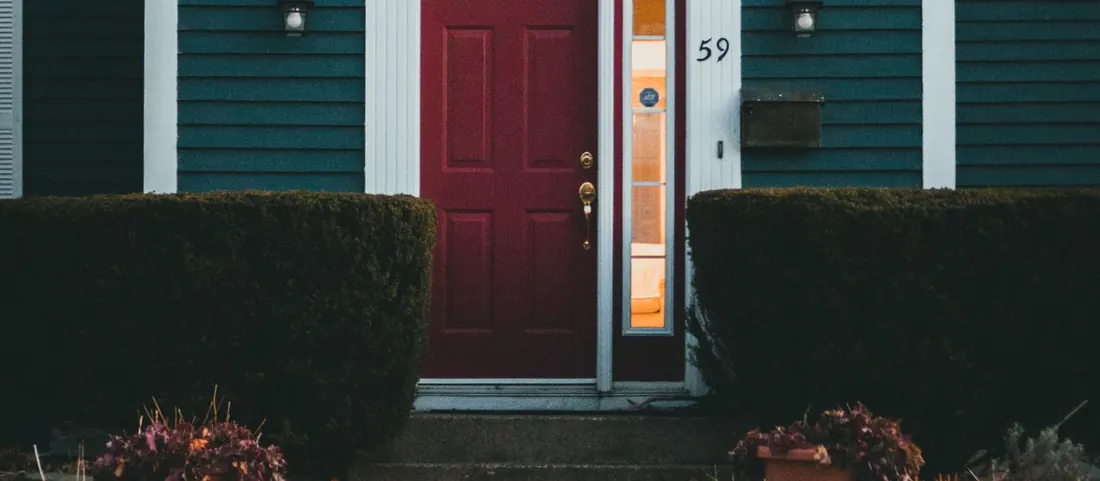 Brick walkway leading to a red front door on a clapboard house