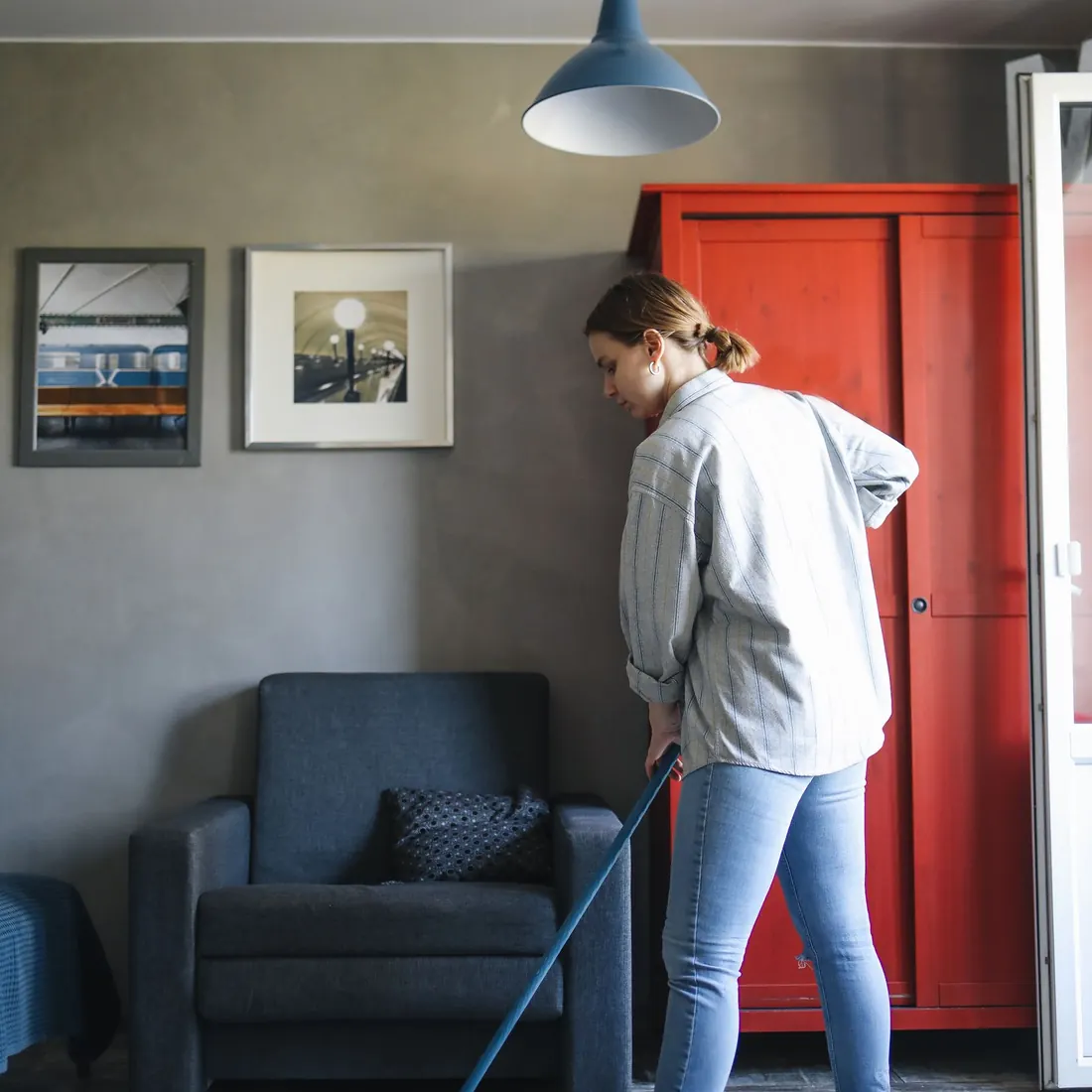 Woman mopping a wood floor in a furnished living room